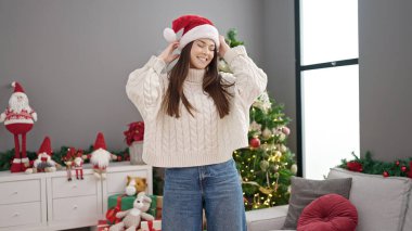 Genç ve güzel İspanyol kadın Noel ağacının yanında durmuş evde dans ediyor.
