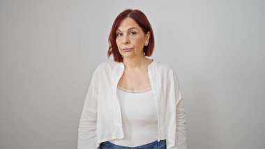 Soyutlanmış beyaz arka planda ciddi bir ifadeyle duran orta yaşlı kadın.