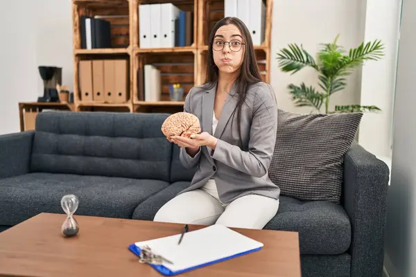 Hispanic Woman Working Therapy Office Holding Brain Puffing Cheeks Funny — Stock Photo, Image