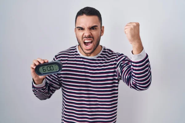 Young Hispanic Man Wearing Pyjama Holding Alarm Clock Annoyed Frustrated — Stock Photo, Image