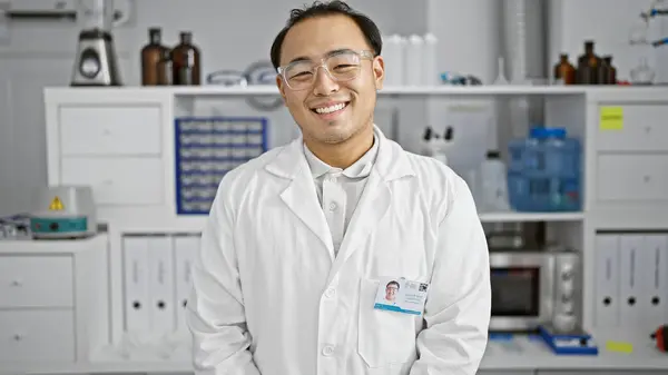 Sparkling smile on a confident young chinese man, a specializing scientist, standing proud in his lab amidst the intricacies of science