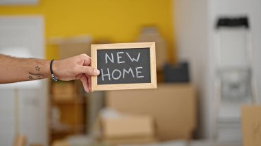 Yeni evinde tahtası olan Latin asıllı genç bir adam.