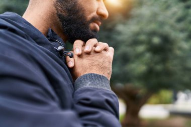 Genç İspanyol adam parkta gözleri kapalı dua ediyor.