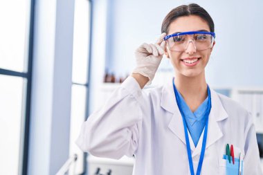 Young beautiful hispanic woman scientist smiling confident standing at laboratory