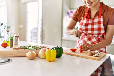 Mutfakta domates keserken gülümseyen güzel İspanyol kadın.