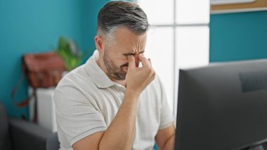 Gri saçlı iş adamı, ofisteki bilgisayarı kullanarak stresli.