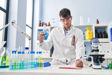 Latin asıllı genç bilim adamı laboratuardaki belgede sıvı yazıyı tartıyor.