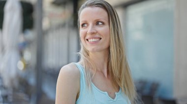 Young blonde woman smiling confident looking to the side at street