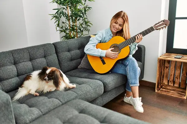 Młoda Kaukaska Kobieta Gra Gitarze Klasycznej Siedzi Kanapie Psem Domu — Zdjęcie stockowe