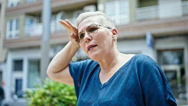 Middle age grey-haired woman sweating at street