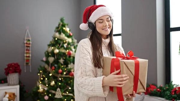 年轻美丽的惊慌失措的女人站在圣诞树旁 抱着礼物在家里跳舞 — 图库照片