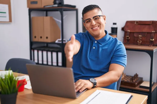 オフィスで働く若いヒスパニック系男性は 笑顔の笑顔で挨拶と歓迎として握手を提供しています 成功したビジネス — ストック写真