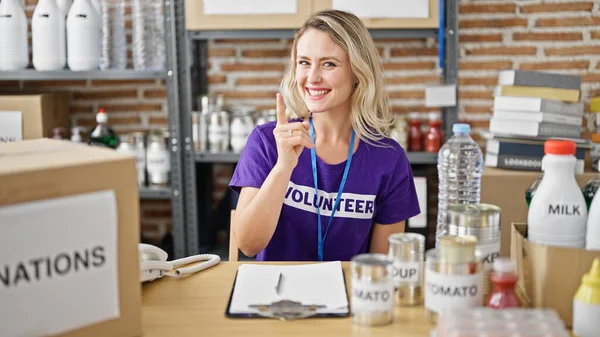 Young Blonde Woman Volunteer Sitting Table Pointing Camera Charity Center — Stock Photo, Image