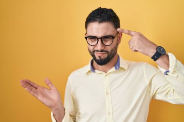 İş elbiseleri ve gözlük takan İspanyol genç adam avuç içi açık fotokopi alanı gösterip, parmağıyla alnını göstermekten rahatsız oluyor. Bunu bir düşün.. 