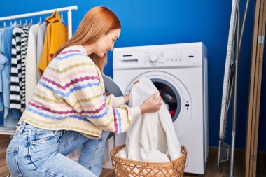 Çamaşır odasında kendine güvenen beyaz bir kadın gülümsüyor.