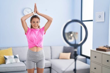 Genç ve güzel İspanyol kadın, evde yoga dersi aldığından emin bir şekilde gülümsüyor.