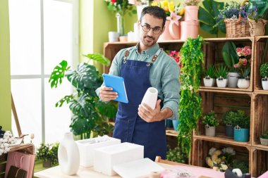 Çiçekçide çiçek saksısı tutan İspanyol bir çiçekçi.