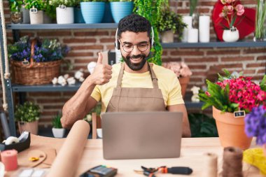 Çiçekçide çalışan İspanyol sakallı bir adam. Video çekiyor. Gülümsüyor, mutlu ve pozitif. 