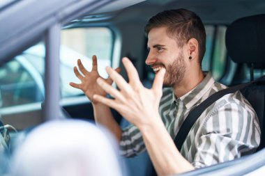 Beyaz bir adam sokakta arabada oturmuş dans ediyor.