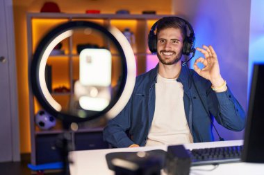 Sakallı İspanyol bir adam akıllı telefonuyla video kaydı yapıyor. Parmaklarıyla imza atıyor, gülümsüyor. Mükemmel bir sembol. 