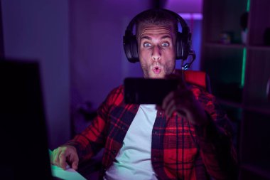 Akıllı telefonuyla video oyunu oynayan beyaz bir genç. Şaşırtmak için ağzı açık kalmış, korkmuş ve şaşırmış. İnanmayan yüz. 