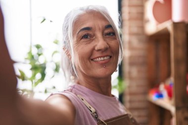 Middle age grey-haired woman florist smiling confident make selfie by camera at florist