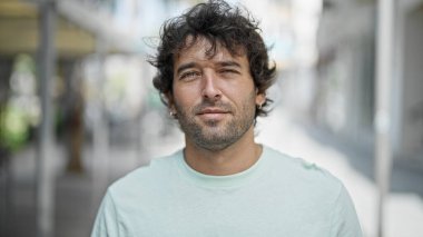 Sokakta ciddi bir ifadeyle duran İspanyol genç adam.