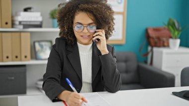 Genç, güzel İspanyol iş kadını. Ofiste akıllı telefon yazısıyla konuşuyor.