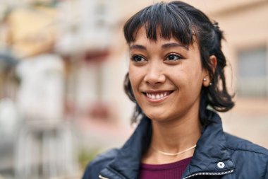 Young beautiful hispanic woman smiling confident looking to the side at street