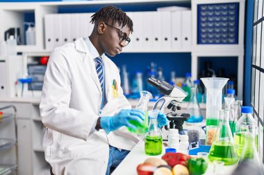 Afrikalı Amerikalı bilim adamı laboratuarda test tüpüne sıvı döküyor.