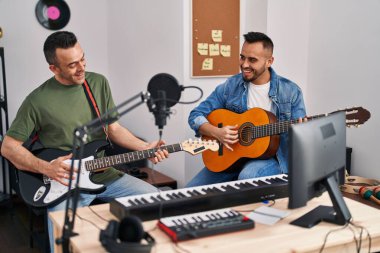 Two men musicians playing classical and electrical guitar at music studio