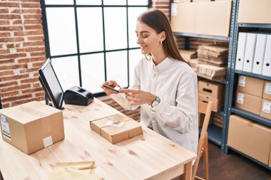 Young caucasian woman ecommerce business worker make photo to package at office