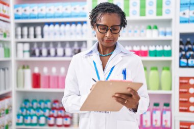 Middle age african american woman pharmacist writing on document at pharmacy