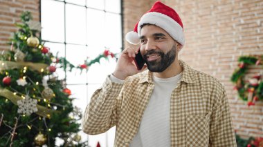 Genç İspanyol adam Noel 'i kutluyor ve evde akıllı telefondan konuşuyor.