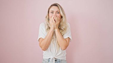 Young blonde woman standing with surprise expression over isolated pink background