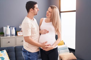 Bir erkek ve bir kadın göbeğine dokunuyor.