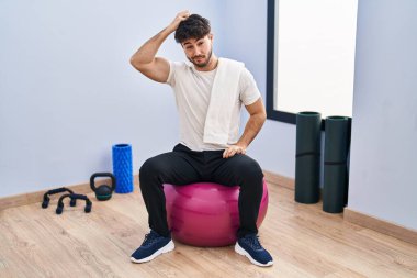 Yoga odasında sakallı İspanyol bir adam pilatese oturmuş soru soruyor. Şüpheyle kararsız, kafa kafaya düşünerek. Düşünceli kavram. 