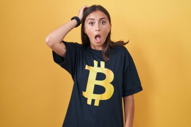 Bitcoin tişört giyen genç İspanyol kadın çıldırmış ve elleri başının üstünde korkmuş, ağzı açık şoktan korkmuş ve şaşırmış. 