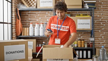 Genç İspanyol gönüllü yardım merkezinde akıllı telefon kullanarak ürünleri kontrol ediyor.