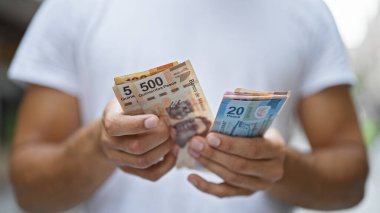 Latin kökenli genç adam Meksika pesolarını sayıyor