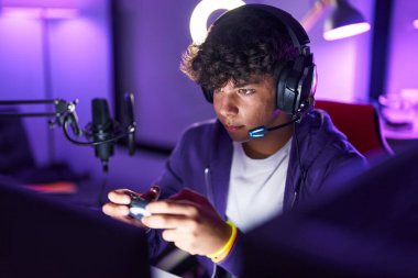 Oyun odasında joystick kullanarak video oyunu oynayan İspanyol asıllı bir genç.