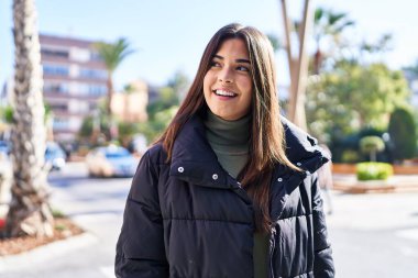 Young beautiful hispanic woman smiling confident looking to the side at street