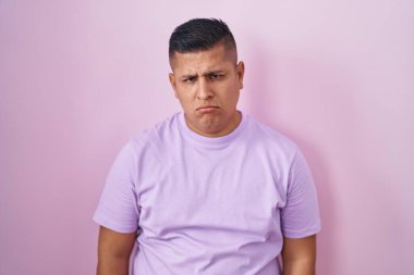 Young hispanic man standing over pink background depressed and worry for distress, crying angry and afraid. sad expression. 