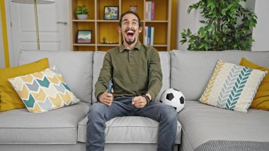 Evdeki kanepede oturan İspanyol futbolu takımını destekleyen genç adam.