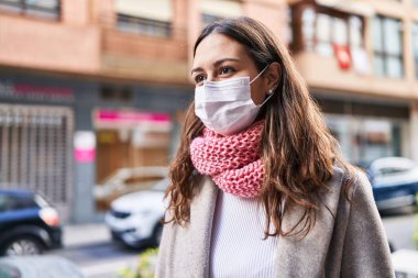 Sokakta tıbbi maske ve eşarp takan güzel bir İspanyol kadın.