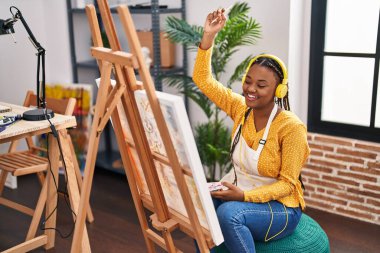 African american woman artist listening to music drawing at art studio