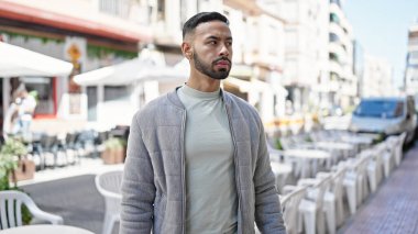 Sokakta ciddi bir ifadeyle duran İspanyol genç adam.