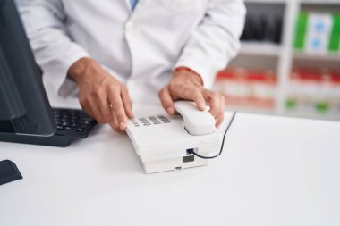 Young arab man pharmacist holding telephone at pharmacy