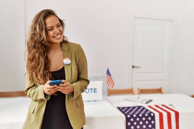 Genç ve güzel İspanyol kadın seçim masası başkanı seçmen kurulunda akıllı telefon kullanıyor.