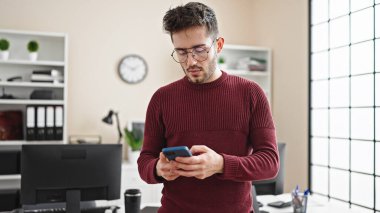 Young hispanic man business worker using smartphone at office